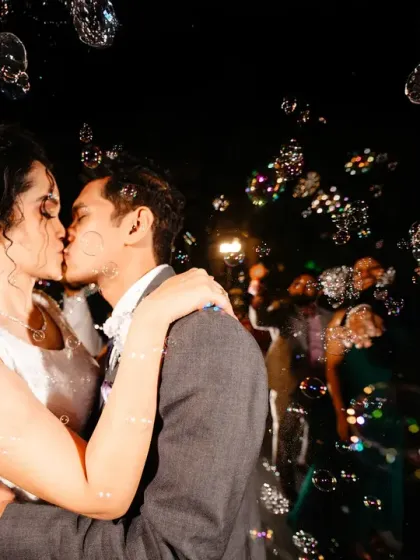A magical moment captured in a flurry of bubbles. The way the light catches each bubble creates a dreamy, festive atmosphere around the couple's kiss.