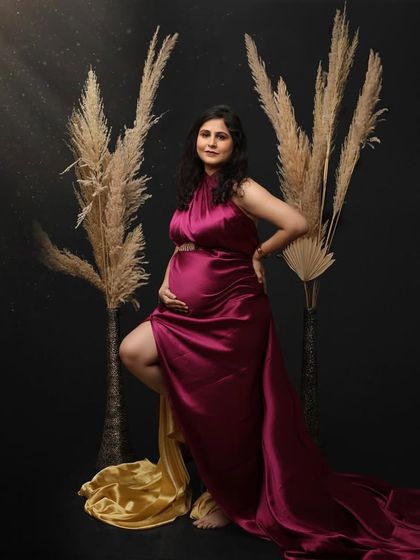 A powerful and confident pose in a magenta satin gown. The dramatic lighting and simple pampas grass props create a modern and stylish fine art portrait.