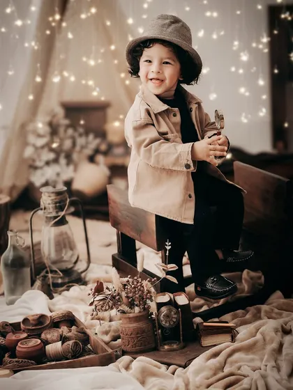 A rustic, camp-themed setup complete with a lantern, wooden toys, and fairy lights. This warm, cozy setting is perfect for capturing the adventurous spirit of a young child.
