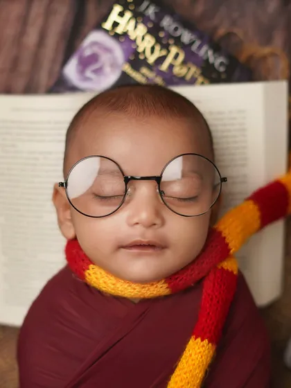 A close-up of our baby Harry Potter, complete with round glasses and a Gryffindor scarf. The details are what make this magical theme come to life.
