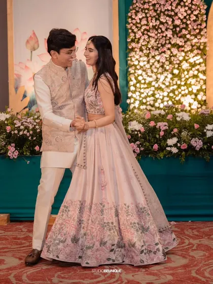 The couple shares a dance in front of a wall of pink and white flowers. I love creating these lush floral backdrops that add romance and beauty to any celebration.