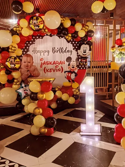 This wide shot shows the complete Mickey Mouse decor, including two large Mickey balloon sculptures flanking the main backdrop, creating a balanced and impactful display.