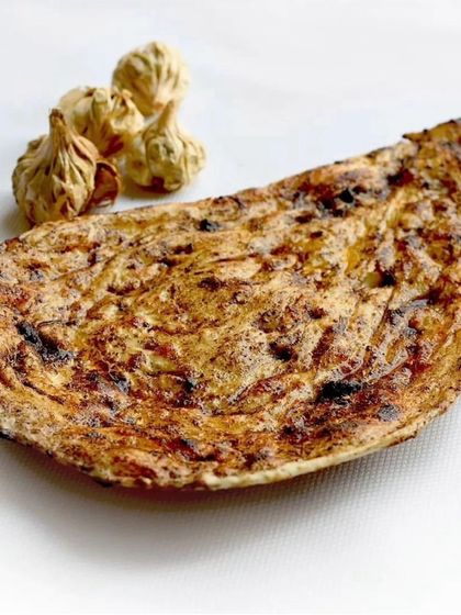 A closer look at our black garlic naan, showcasing its rustic, charred texture and the deep, savoury flavour it brings to the table.