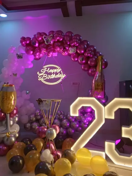 A glamorous 23rd birthday setup with a balloon arch in purple and pink chrome balloons. The champagne and wine glass foil balloons add a fun, celebratory touch.