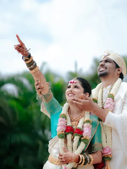 A beautiful candid moment during a South Indian wedding ritual, where the couple looks towards the sky together, full of hope and happiness.
