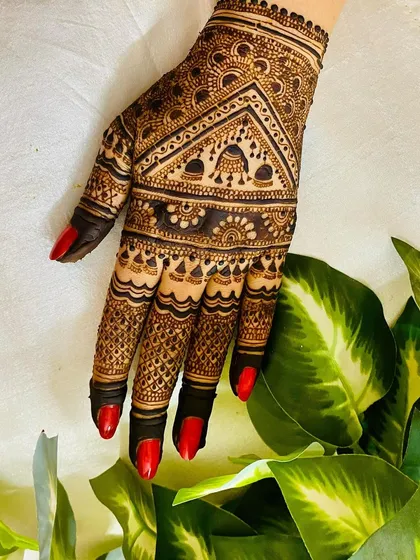 A classic design featuring a geometric pattern on the back of the hand. The fingers are adorned with detailed jaal work, and the dark stain looks striking against the red nails.