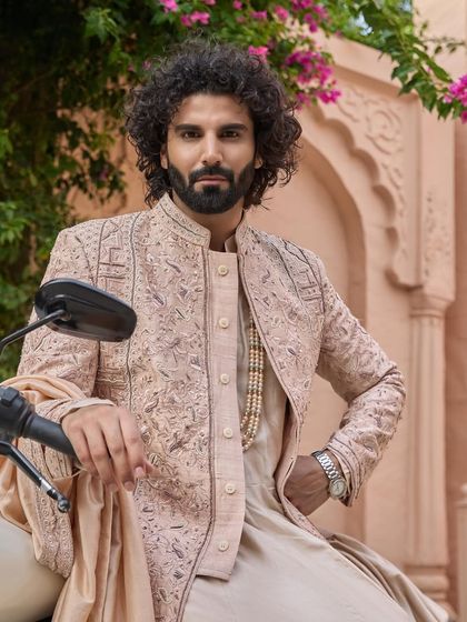 The modern groom makes his entrance. This shot pairs the traditional elegance of the sherwani with a contemporary prop, showcasing a confident and stylish personality.