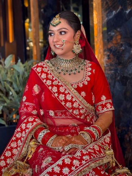 A candid shot of our bride in her red lehenga. The soft lighting highlights her dewy makeup and the intricate white embroidery of her outfit.