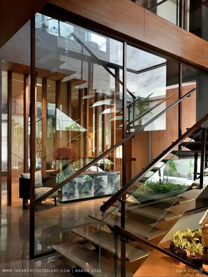 The T House was designed to respond to a gorgeous Alistonia tree, with terraces and decks stepping back to honor it. This view shows the glass-enclosed staircase, which allows light to flood the interiors while maintaining a visual connection to the greenery outside.