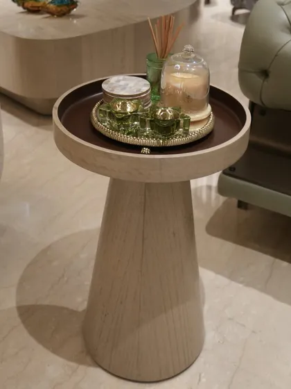 This elegant side table is wrapped in oak veneer with a matte finish, showcasing the beauty of natural wood grain on a curved form. It’s a simple yet sophisticated piece that complements the muted tones of the living room.