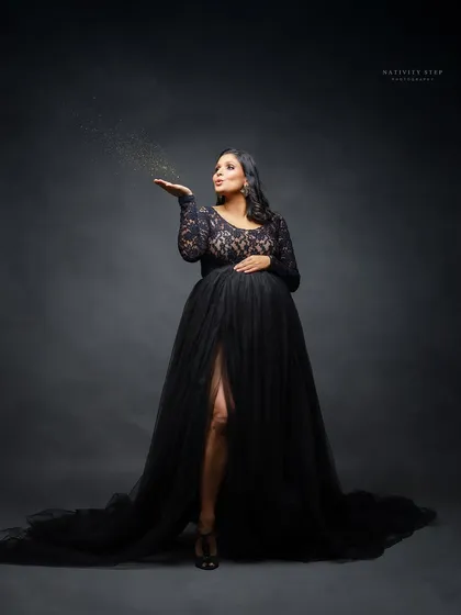 A magical moment as the mother-to-be blows golden glitter. This adds a touch of sparkle and celebration to the classic black gown portrait.