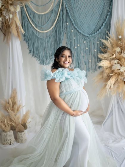 A radiant smile from the mom-to-be. This portrait showcases her happiness against a backdrop of soft blue and neutral-toned boho decor.