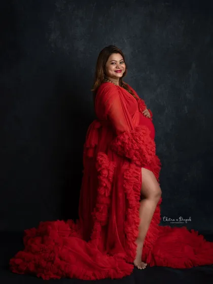 Confident and radiant in red. This classic pose with a side slit gown is a favorite for showing off both the baby bump and a bit of glamour.