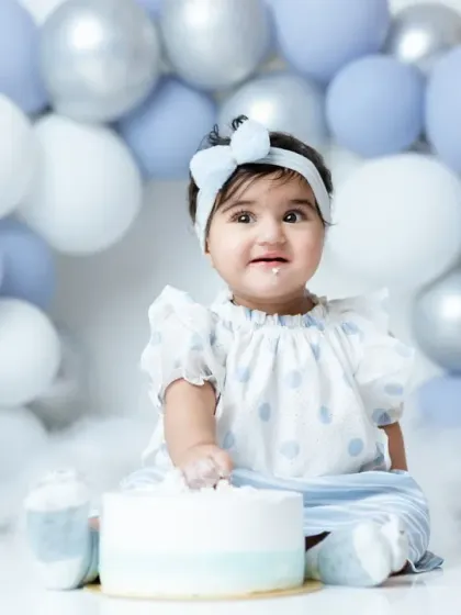 This little girl is having a wonderful time at her first birthday cakesmash, with a cute bow and a face full of frosting.