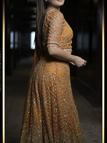 A side profile of the burnt orange lehenga, highlighting the delicate embroidery on the sleeves and the beautiful drape of the fabric.