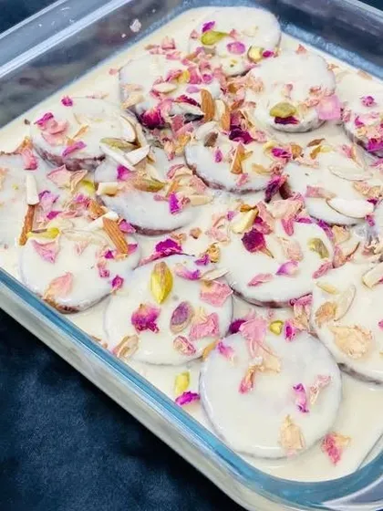This beautiful dessert consists of sweet discs soaked in a creamy base, garnished with slivered almonds, pistachios, and dried rose petals. It's as beautiful to look at as it is delicious to eat.