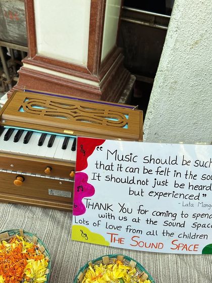 A beautiful, handmade card from our students alongside the harmonium gifted to Shawn Mendes, with a quote from Lata Mangeshkar.