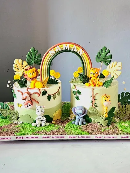 Perfect for a joint celebration, this jungle-themed set features two connecting cakes. I handcrafted all the adorable fondant animals, including a lion, tiger, elephant, and monkey, and brought the scene to life with a sugar rainbow and edible tropical leaves. This design shows how I can create a cohesive and impressive display for any party.