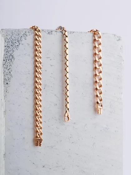 A wider composition of the gold chains, showing three different link styles. The clean, bright lighting and simple background make this a perfect shot for a catalog or product page, allowing customers to compare the designs easily.