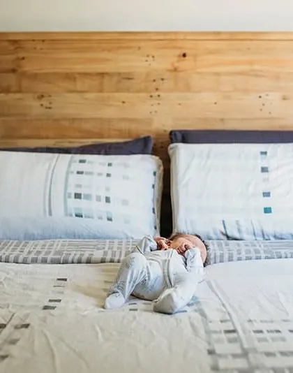 A wide shot showing just how small a newborn looks on a big bed. This perspective helps tell the story of their first days at home.