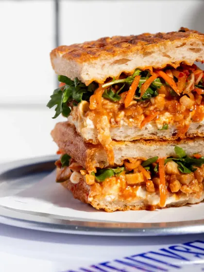 A close-up shot revealing the juicy pulled pork and crunchy kimchi slaw inside the focaccia sandwich.