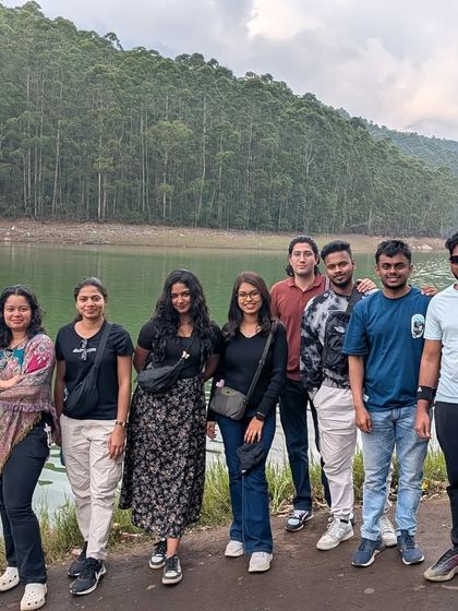 A group photo by the serene Mattupetty Dam near Munnar, surrounded by forests and calm waters.