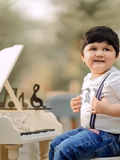A confident little musician adjusting his suspenders. His playful personality comes through in this charming outdoor portrait.