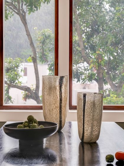 A close-up of the decor on the dining table, where the texture of the vases and bowl contrasts beautifully with the sleek, dark surface of the table.
