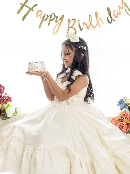 The birthday girl holds her cake, smiling happily in her dreamy, cloud-themed birthday setting.
