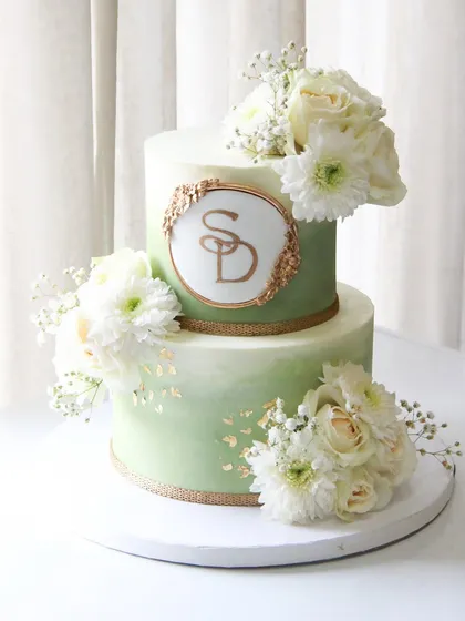 An engagement marks the start of a beautiful story, and this cake was designed to capture that feeling. I used a modern sage green ombre effect on my signature smooth ganache, adorned with fresh white florals and a touch of gold leaf for a look of timeless elegance.