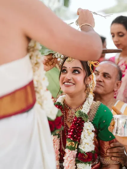 A precious moment from a South Indian wedding ceremony. The bride's makeup is soft and minimal, allowing her joyful expression to be the focus.