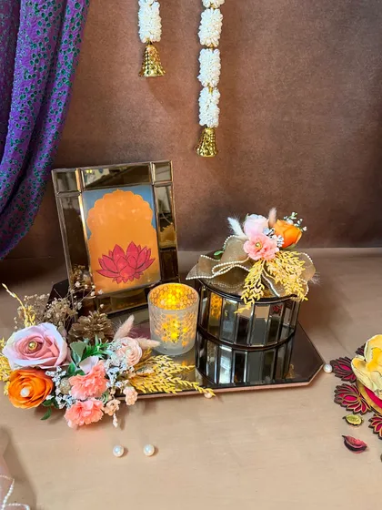 This Diwali hamper combines spiritual and festive elements, with a lotus painting in a golden frame and a mirrored box. The warm orange and pink tones are perfect for the season.