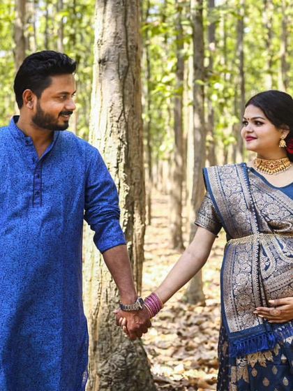 A maternity shoot featuring beautiful traditional Indian attire. The couple walks hand-in-hand through a sunlit forest, blending culture and nature.