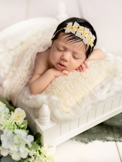 An angel sleeping on a tiny white bed, surrounded by lace and white flowers. This setup is all about purity, elegance, and innocence.
