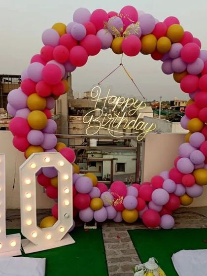 This vibrant balloon ring in shades of pink, purple, and yellow is perfect for a fun and colorful birthday party. The setup also includes a large light-up marquee number '10' for a tenth birthday or anniversary.
