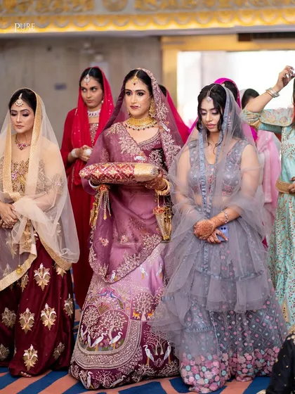 The bride's entrance during the Anand Karaj ceremony, surrounded by her bridesmaids. A moment filled with anticipation and emotion.