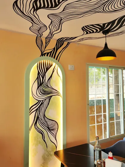 For Essence Cafe, we created art that's part of the architecture. This piece features a hand-painted abstract design inside a backlit arched niche, with the pattern flowing out and across the ceiling.