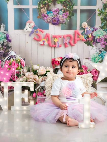 A princess at her first birthday party. The light-up 'ONE' and star props add a touch of magic to this enchanting floral setup.