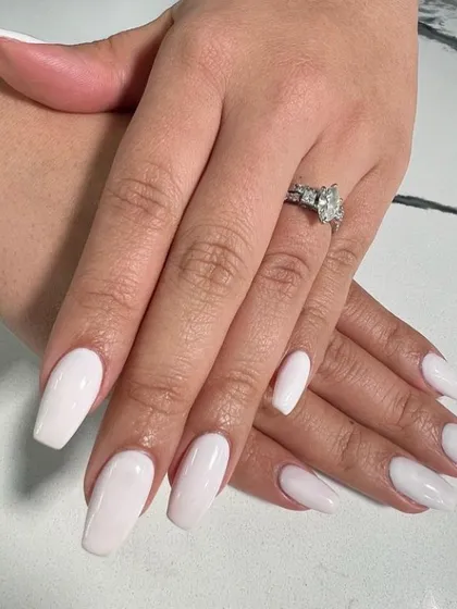 A clean and classic solid milky white manicure on coffin-shaped nails, perfect for an elegant and modern bride.