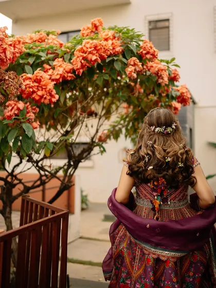 A beautiful shot from the back, showing the hairstyle with delicate floral accessories and the flow of the stunning lehenga.