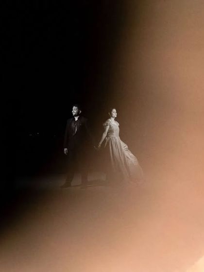 An artistic shot using a foreground element to create a golden flare effect. This technique frames the couple in a unique way, adding a dreamy and magical quality to the photo.