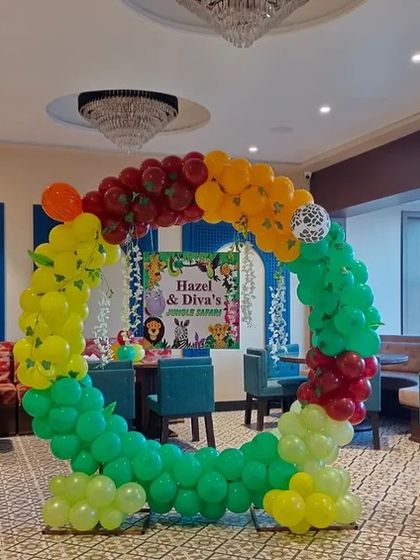 A jungle-themed circular balloon arch used as a photo booth or cake-cutting backdrop inside the venue.