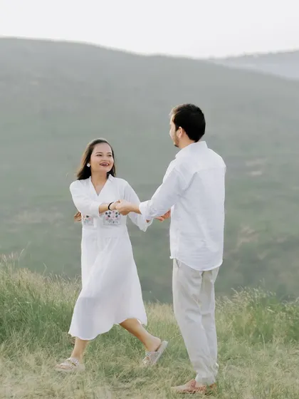 A fun and dynamic shot of the couple dancing and twirling in a vast green field.