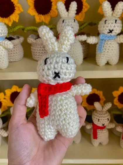 A close-up of a white amigurumi bunny, showing the hand-stitched face details.