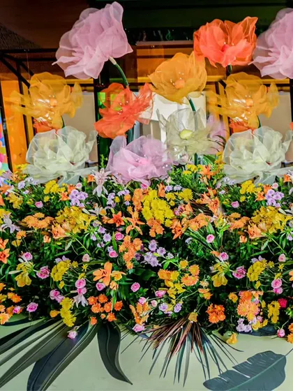 A vibrant floral arrangement for the Coachella Haldi, featuring a mix of colorful flowers and oversized, translucent fabric flowers for a touch of whimsy.