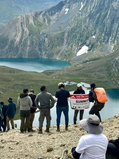 We made it. The feeling of reaching the summit with the group, overlooking a turquoise lake, is indescribable. A moment of shared accomplishment and awe on our Kashmir trek.