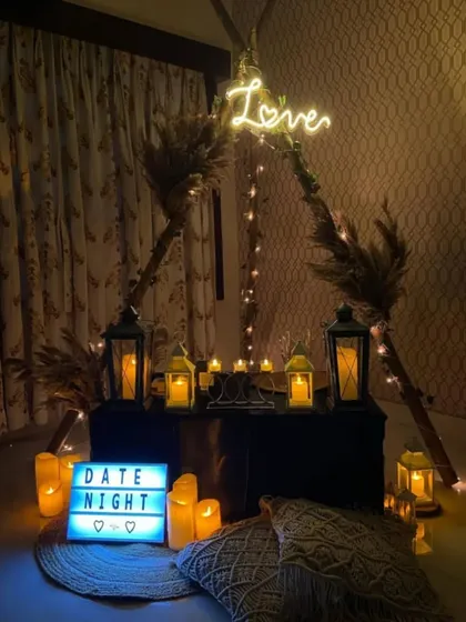 For a cozy and personal evening, I created this intimate date night setting. It features a boho-style teepee frame, warm candlelight from lanterns, a custom 'Love' neon sign, and comfortable floor seating with macrame pillows, perfect for a private celebration at home.