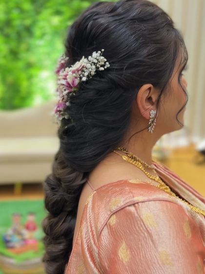 A side view of a soft, voluminous pull-through braid with a delicate floral accessory, perfect for a baby shower or engagement.
