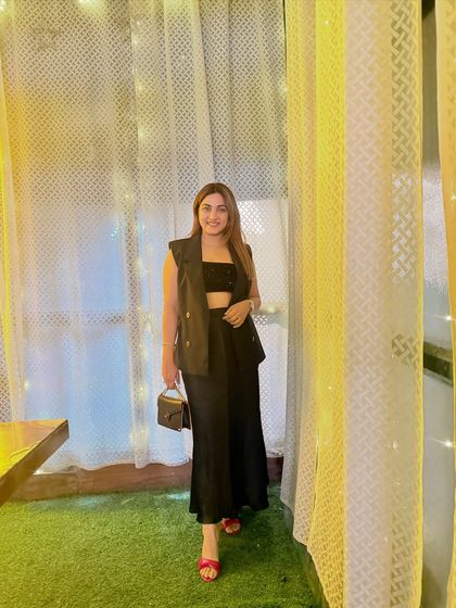 The fairy lights in the background add a magical touch to this chic evening look. The outfit is perfect for a dinner date or a night out, proving that black is never boring when styled right.