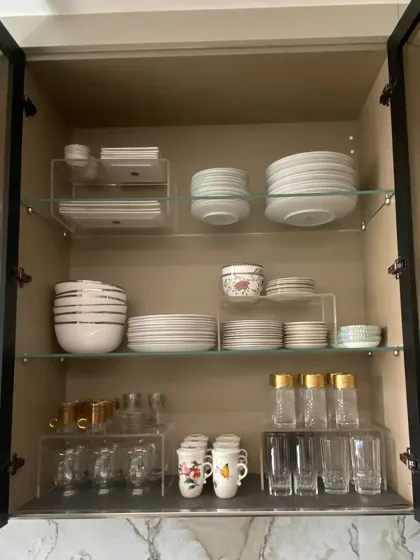We used acrylic risers in this cabinet to create separate zones for different types of plates, bowls, and glasses, making the most of the available shelf height.